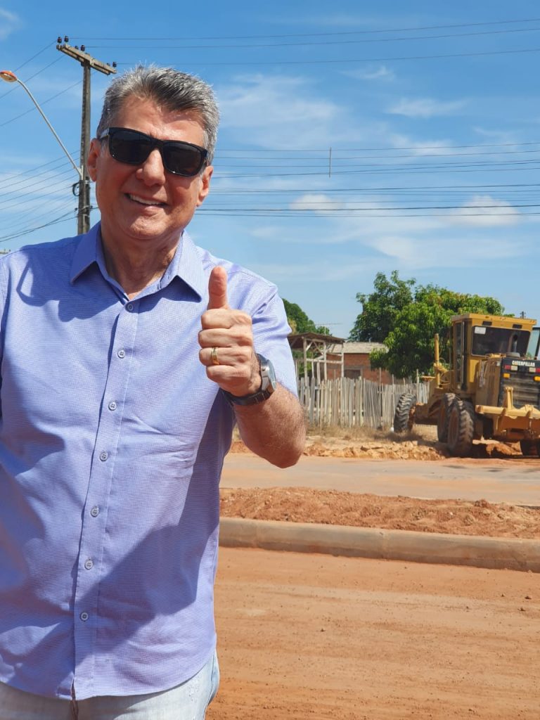 Romero Jucá faz sinal de legal enquanto visita obra de asfalto no Jardim Tropical 