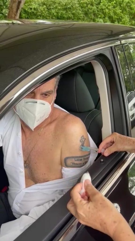 Romero Jucá dentro do carro com ombro a mostra recebe primeira dose da vacina contra a covid