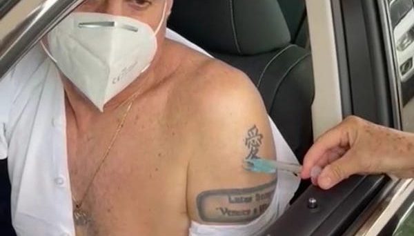 Romero Jucá dentro do carro com ombro a mostra recebe primeira dose da vacina contra a covid