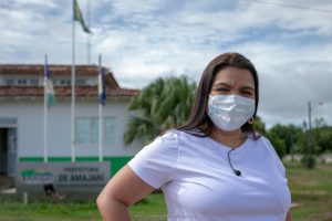 Núbia Oliveira de camisa branca em frente da Prefeitura de Amajari