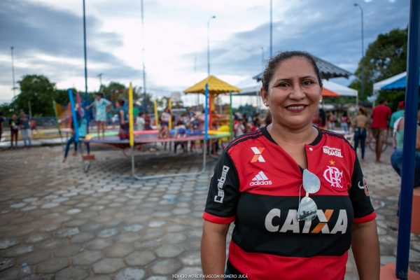 Hudislane Rodrigues usa a camisa do Flamengo e sorri com praça ao fundo