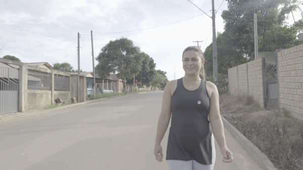 Kassia Rodrigues com roupa de caminhar sorri com o asfalto em Caroebe