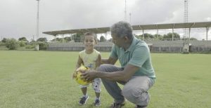 Zezinho junto com o filho no campo da Vila Olímpica de Iracema. Ele ensina que o esporte salva vidas
