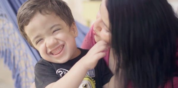 Miguel sorrindo em abraço da mãe mostra a saúde da criança