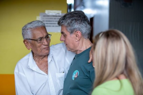 Romero Jucá e Teresa Surita olham para um homem de cabelos brancos que está sorrindo